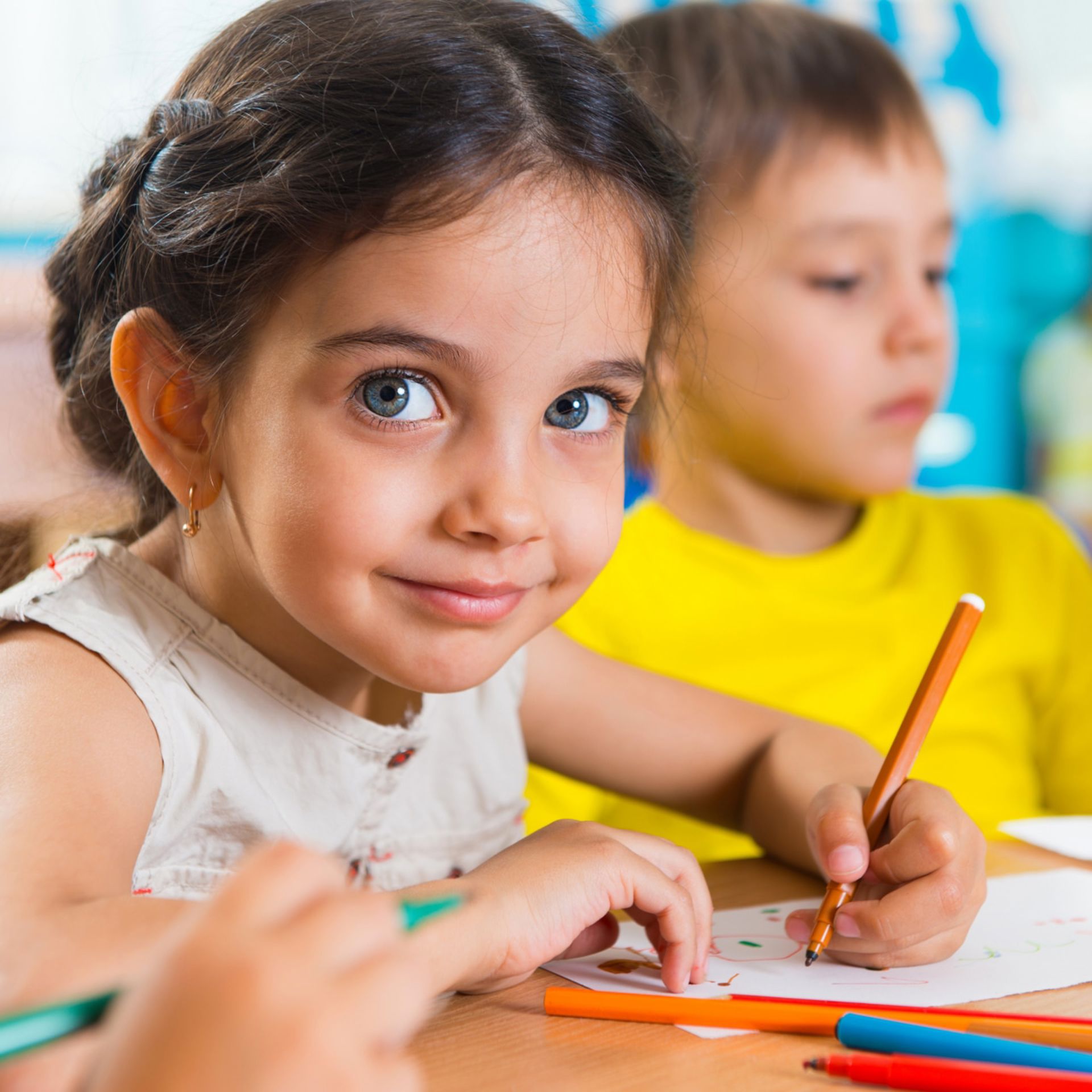 Blue eyed girls drawing and smiling at the camera