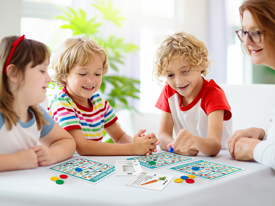  A woman playing bingo with 3 kids sitting at a table