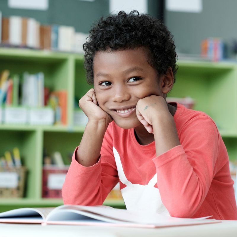 Young boy smiles to the camera in class